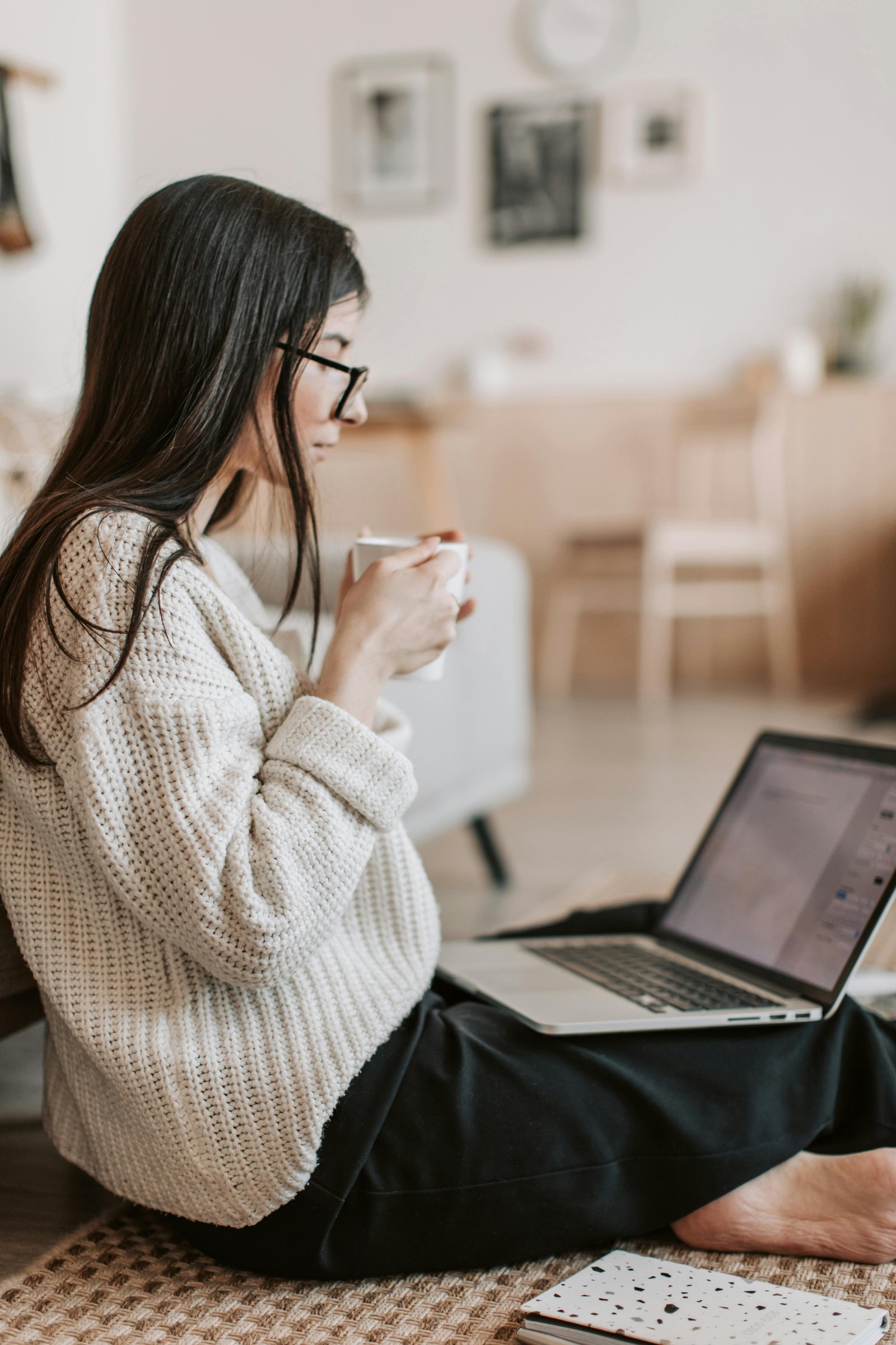 Woman sits on carpeted floor working on her computer